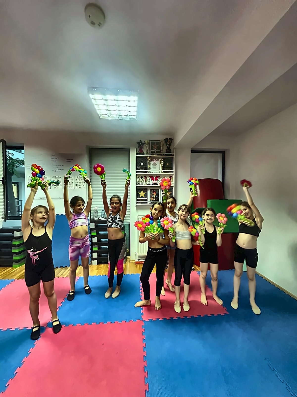 Grupă de cursante Happy Star cu buchete, în sala cu trofee